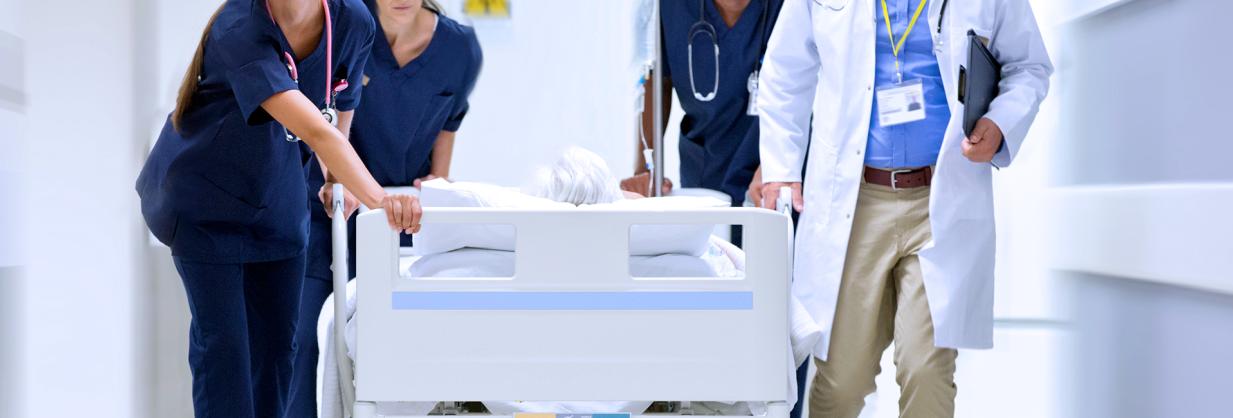 Healthcare team standing beside a hospital bed