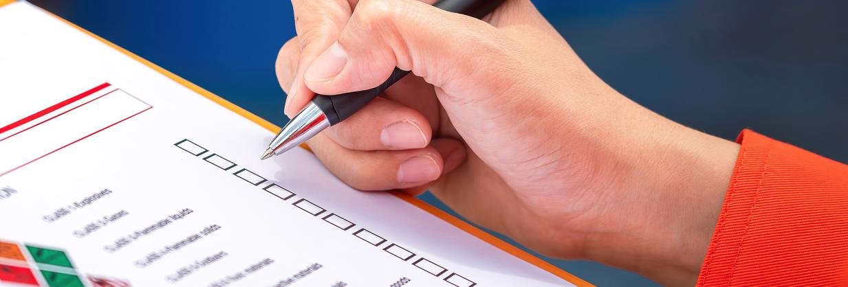 Hand holding a pen, completing a form