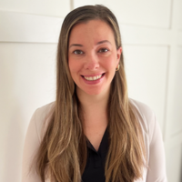 woman with long blonde/brown hair wearing a white sweater over a black blouse