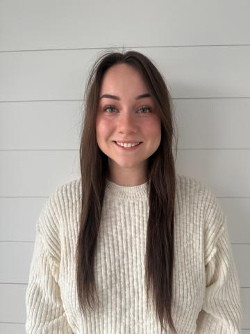 Photo of a woman with long brown hair wearing a white long sleeve shirt