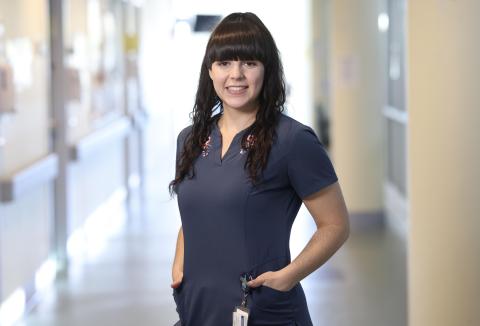 A woman with long brown hair wearing navy blue scrubs